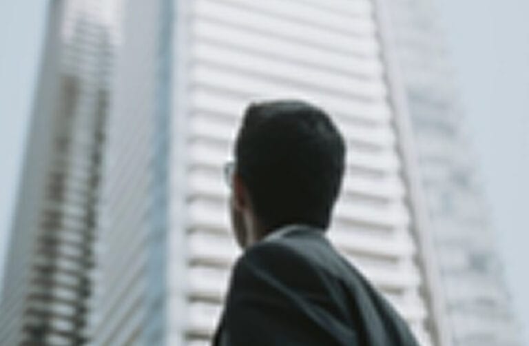 Male outside looking up at a skyscraper building