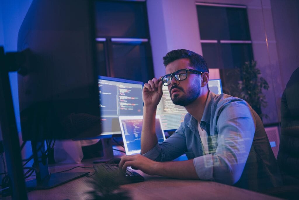 a man sat working with multiple screens of code