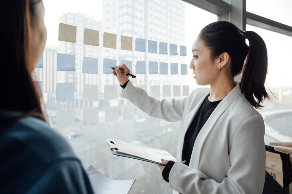 young woman writing on post it notes on a window